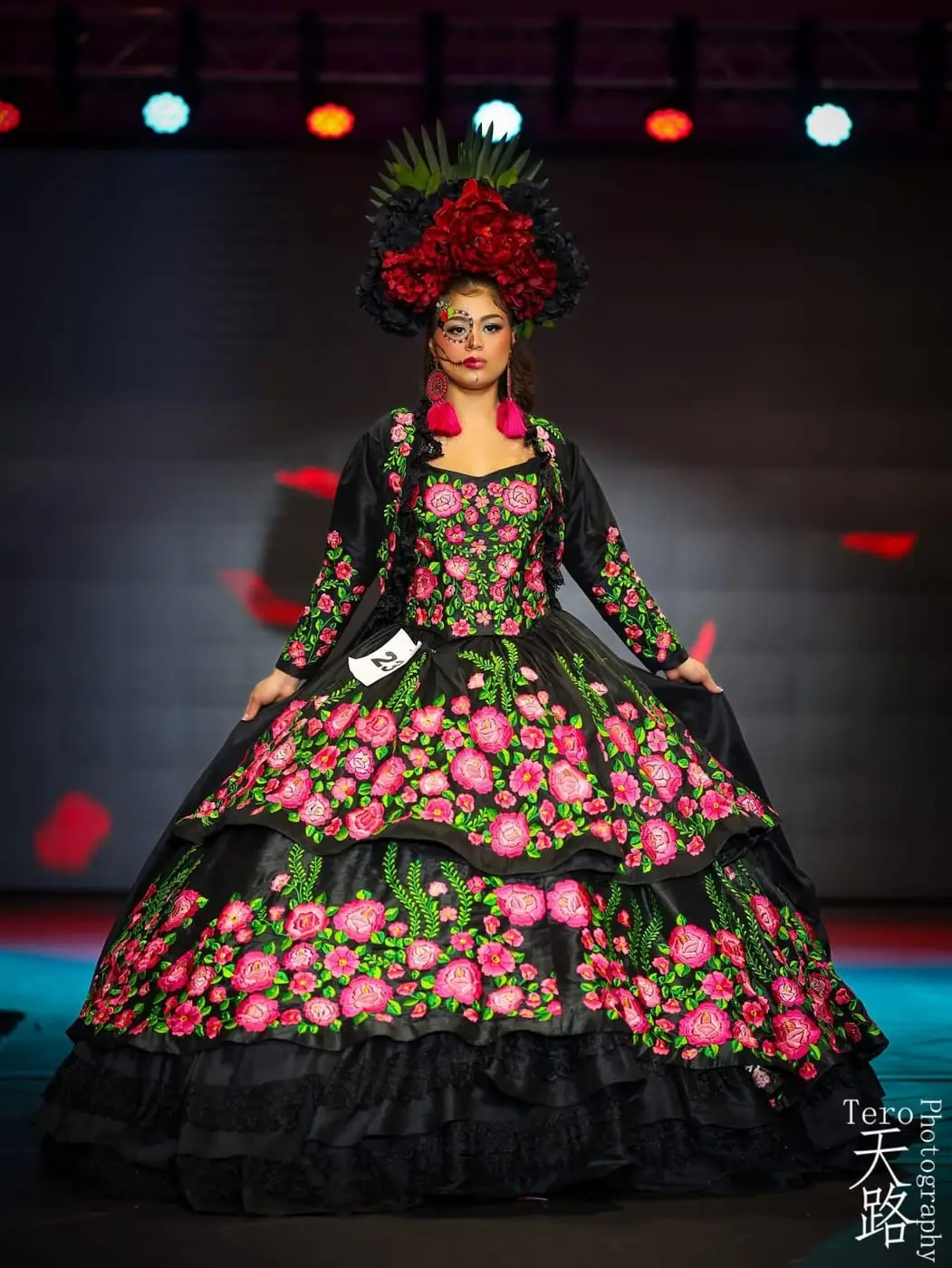 A contestant in a black Mexican costume embroidered with pink roses and a floral headdress