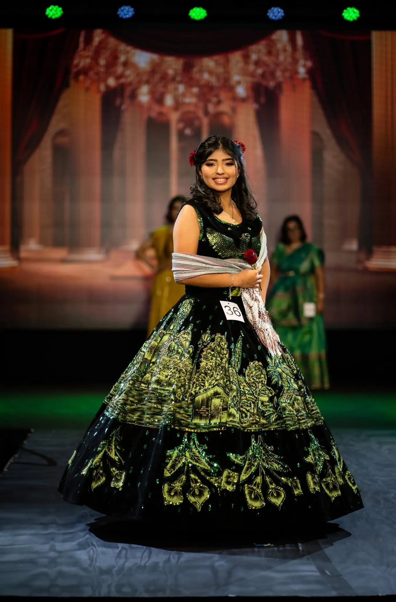 A contestant in an embroidered ball gown on stage