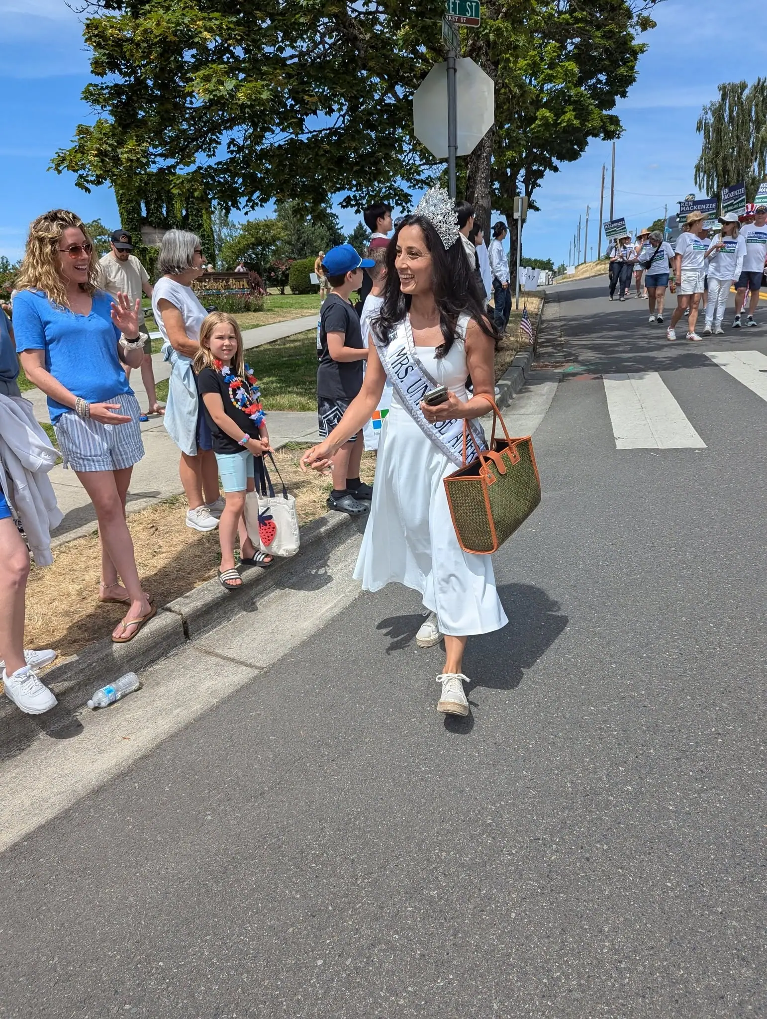 A titleholder greeting families along a parade route