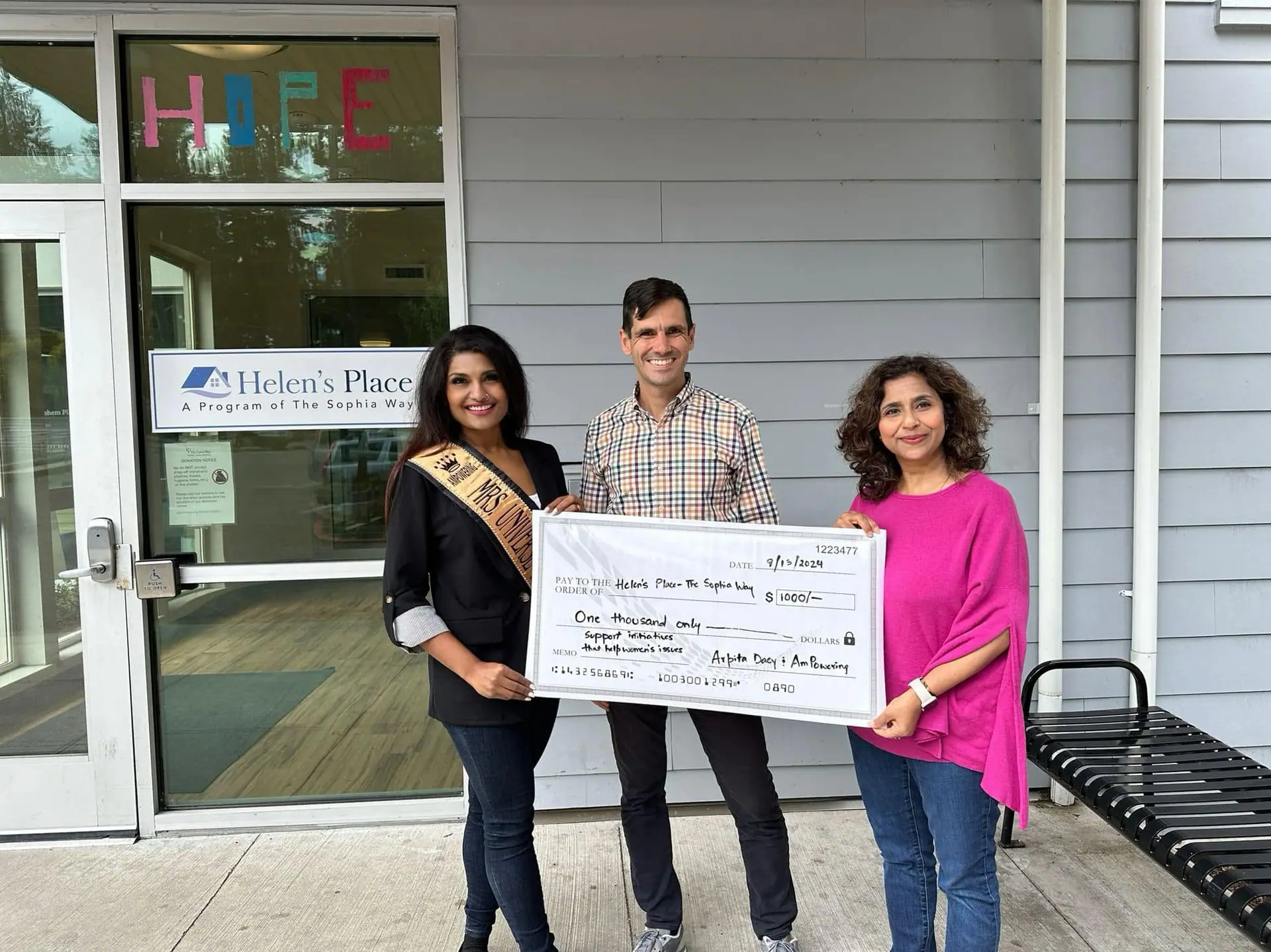 A titleholder presenting a donation at Helen's Place