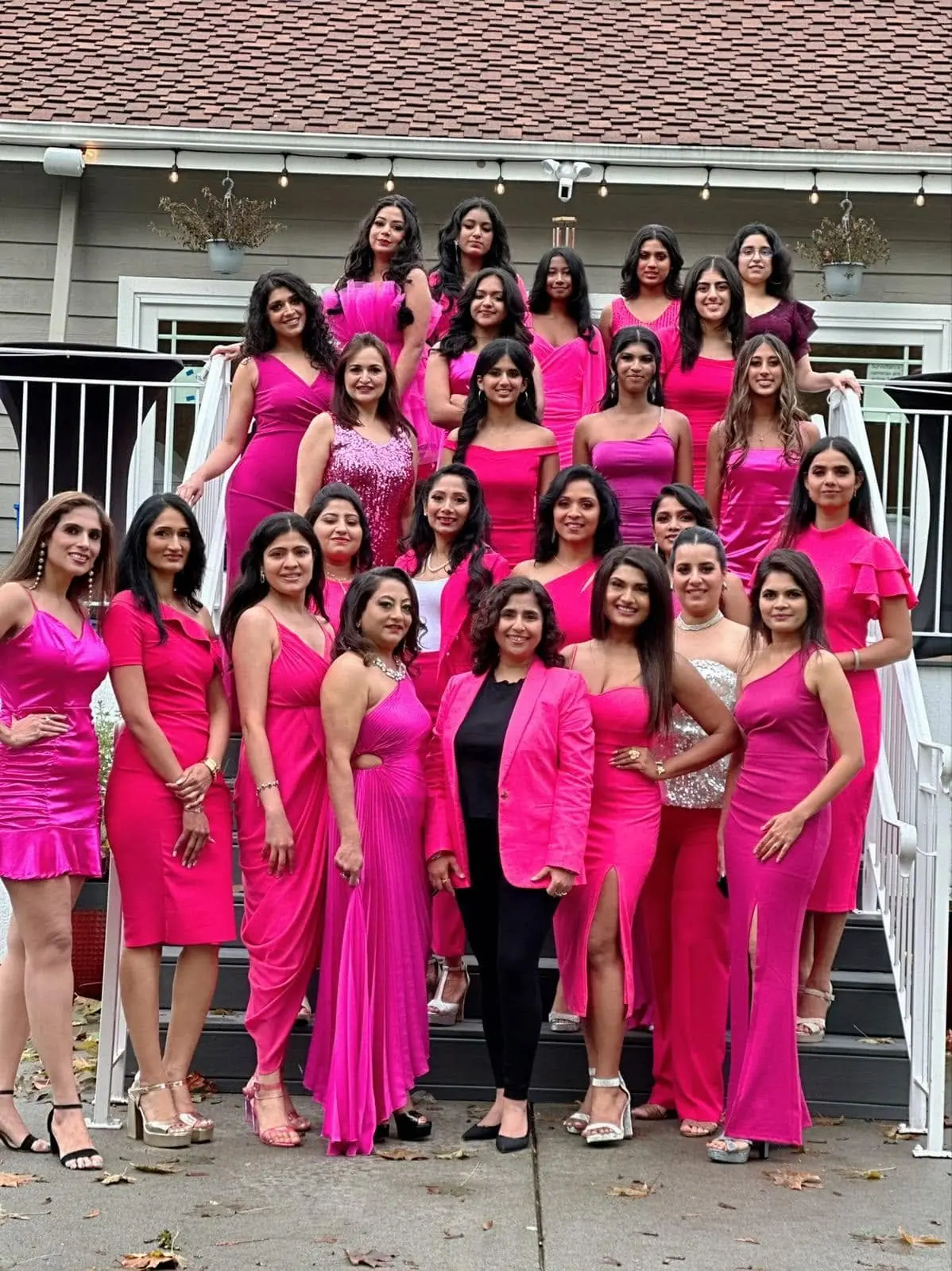 About thirty contestants and titleholders dressed in pink on a flight of outdoor steps