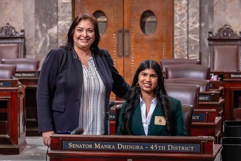 A titleholder serving as a Senate page, seated at Senator Manka Dhingra's desk with an AmPowering representative