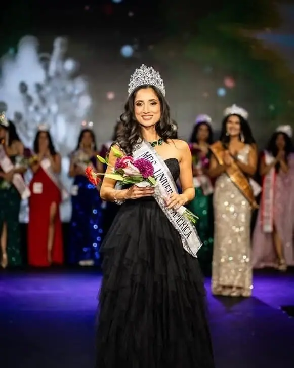 A Mrs Universe America titleholder crowned on stage, holding flowers