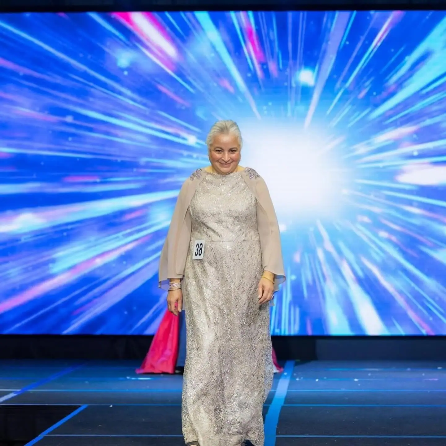 A senior contestant in a silver lace gown walking the stage